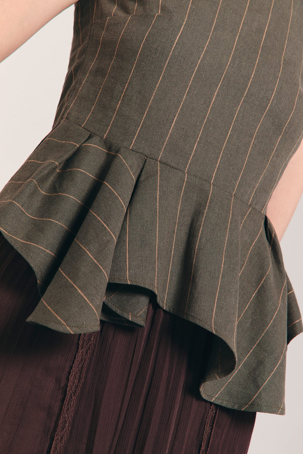 Blusa verde sin mangas de raya diplomática con peplum asimétrico en cintura