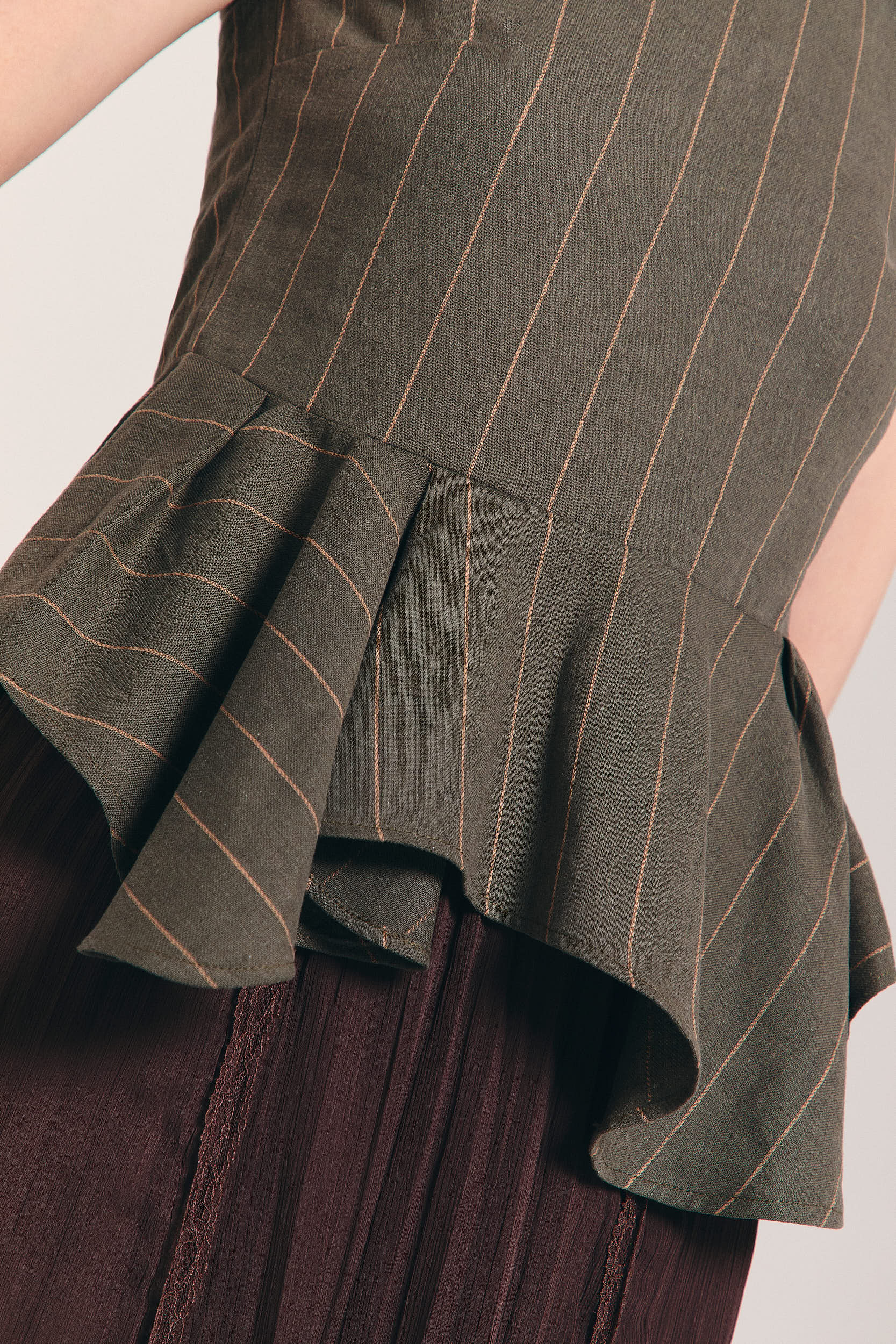 Blusa verde sin mangas de raya diplomática con peplum asimétrico en cintura